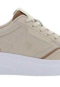 Beżowe sneakersy z gładką syntetyczną cholewką, teksturowanymi brązowymi akcentami, białą gumową podeszwą i sznurowaniem. Zawierają wytłoczone logo po boku.