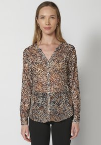 Camicia con bottoni realizzata in tessuto leggero e trasparente, caratterizzata da un motivo a foglie multicolore nei toni del marrone, crema e blu scuro, con maniche lunghe.