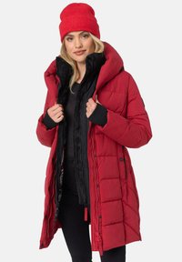 Red puffer coat with a quilted design, black inner lining, and large hood. Paired with a red knit beanie. Features elastic cuffs and zippers.