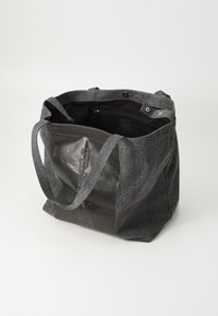 Grå tote-veske i stoff med lærdetaljer, som har to håndtak, en innvendig lomme og trykknapplukking. Teksturen varierer mellom materialene.