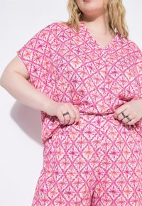 Roze gemusterde set van twee delen met een losse top met v-hals en broeken met elastische tailleband en bloemenmotieven.