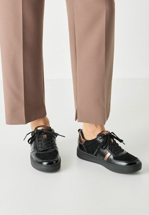 Sneakers neri caratterizzati da una combinazione di materiali in vernice lucida e suede opaco, con un accento metallico e lacci rotondi.