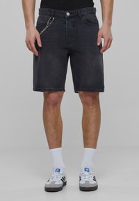 Donkerdenim shorts met een slim fit, voorzien van een zilveren kettingaccent, vijf zakken en een nette zoom, gecombineerd met witte sokken en sneakers.