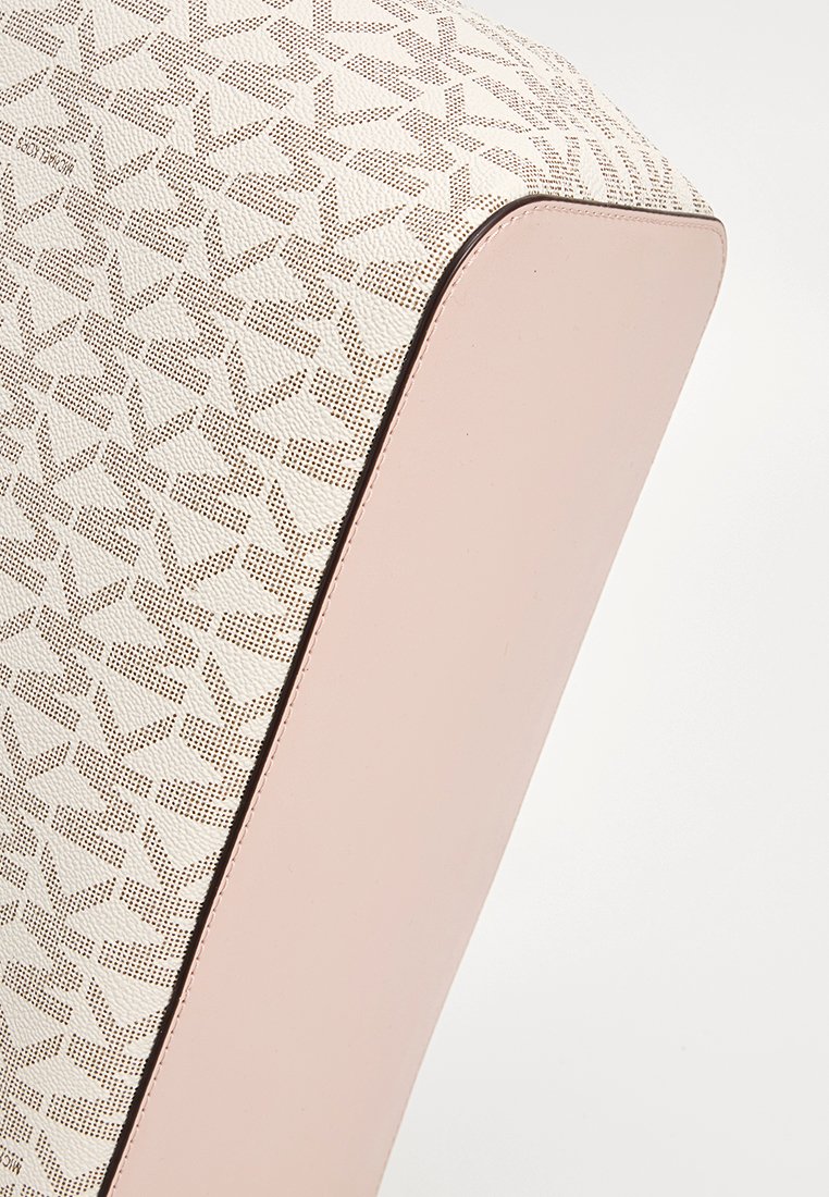 Mehrschichtiger Sitz mit einem cremefarbenen, gemusterten Stoff und einer weichen rosafarbenen Basis, mit einer glatten Oberfläche und abgerundeten Kanten.