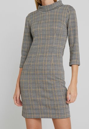 Geruite jurk in zwart, wit en mosterdgeel, met een hoge kraag en driekwart mouwen, gemaakt van een getailleerde, rekbare stof.