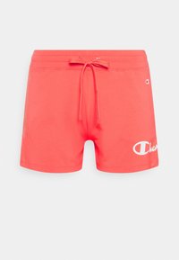 Korallfärgade sportshorts med dragstring i midjan, tillverkade av mjukt tyg. Har en stor vit logo på nedre vänstra sidan.