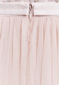 Jupe en tulle rose clair avec un design texturé et superposé. Dispose d'une taille lisse et d'une fermeture éclair au dos.