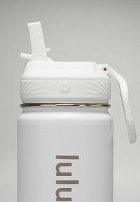 Weiße Wasserflasche aus rostfreiem Stahl mit strukturiertem Griff, einem Klappdeckel und einem silbernen Band nahe dem Boden. Markenlogo sichtbar.