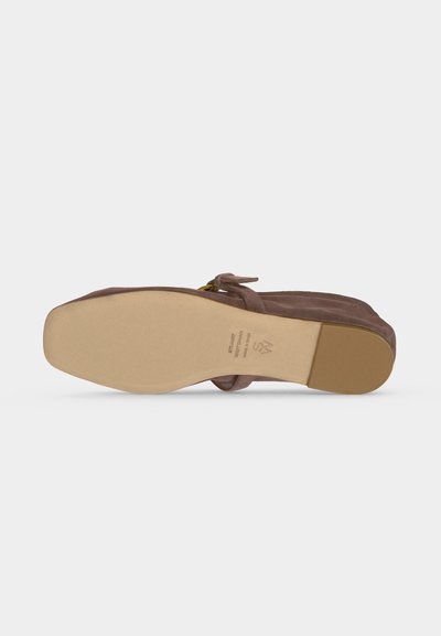 Semelle d'une chaussure plate en suède marron avec un bout carré et un petit talon, vue de dessous sur fond blanc.
