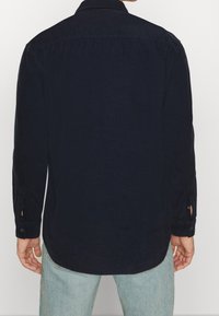 Granatowa koszula z długim rękawem, prostym dołem i mankietami zapinanymi na guziki. Posiada kołnierz oraz fakturowaną bawełnianą tkaninę. Prosty design bez wzorów.