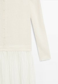Langärmliges Kleid aus einem hellcremefarbenen Stoff mit strukturiertem Oberteil und einem fließenden, plissierten Rock. Mit Knopfverschluss und schlichter Gestaltung.