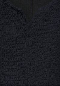Tessuto nero testurizzato con scollo a V, caratterizzato da linee ondulate che creano un effetto 3D sulla superficie. Design pulito e minimale.