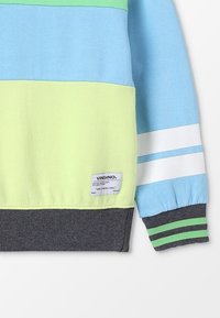 Sudadera a rayas en azul claro, verde y amarillo, con dobladillo gris, que presenta una etiqueta, rayas blancas en las mangas y puños acanalados.