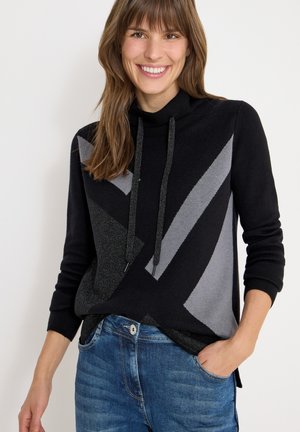 Maglione a fantasia nera e grigia con collo a cowl e cordoncini, caratterizzato da disegni geometrici e una vestibilità comoda, abbinato a jeans blu.