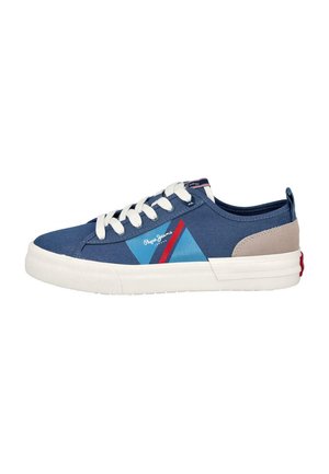 Zapatilla deportiva baja de lona azul con cordones blancos, suela blanca, parche beige en el talón y logo triangular azul-rojo en el lateral.