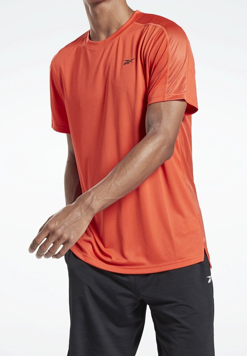Camiseta deportiva de manga corta para hombre en un vibrante color naranja, con tejido transpirable, aberturas laterales y un pequeño logotipo negro en el pecho.