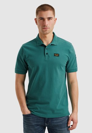 Camisa polo en color azul verdoso, hecha de algodón, con un cuello clásico, tres botones y un pequeño parche con logo en el pecho. Mangas cortas.
