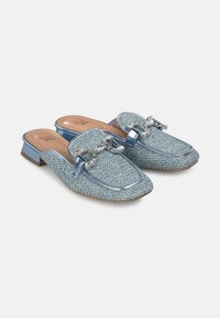Light blue slip-on mules with a textured woven upper, patent accents, and a decorative chain detail on the front. Low block heel.