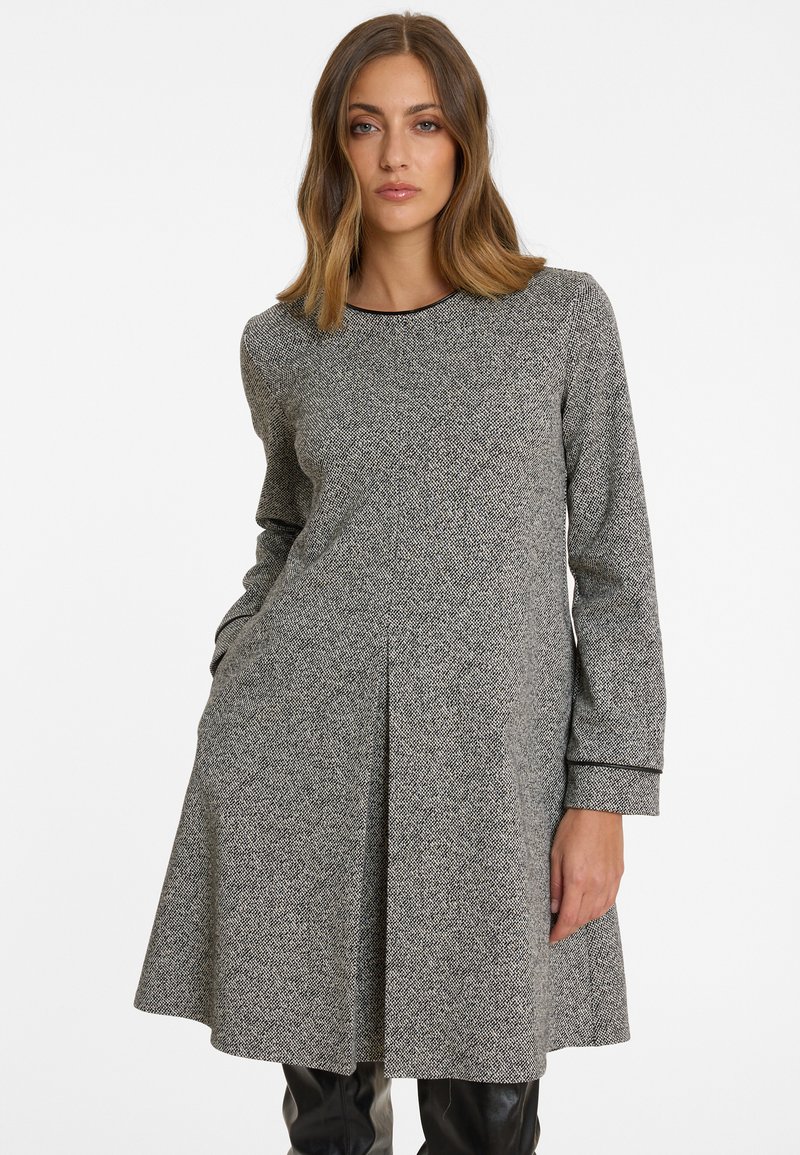 Graues Strickkleid mit langen Ärmeln, rundem Ausschnitt und ausgestellter Silhouette. Verfügt über eine subtile Textur und Seitentaschen; besetzter Saum.