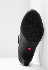 Zwarte leren zool met een gestructureerd bloemmotief, rode ronde knop met het label 'CAMPER', maat '37' en zachte contouren langs de zijkanten.