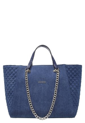 Blaue gesteppte Tragetasche mit silbernen Kettengriffen und dem "GUESS"-Logo mittig auf der Vorderseite, vor weißem Hintergrund.