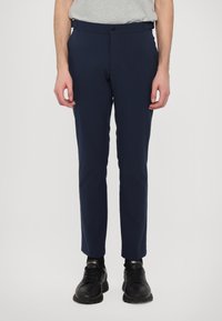 Tumed sinine, slim-fit püksid, mis on valmistatud siledast kangast. Omab nööbivärgiga sulgemist, vöörihmasid ja kahte küljetaskut. Kanda mustade tossudega.