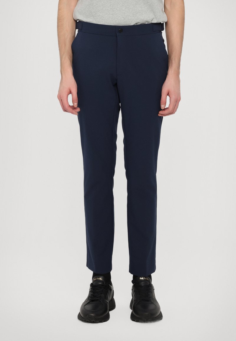 Tumed sinine, slim-fit püksid, mis on valmistatud siledast kangast. Omab nööbivärgiga sulgemist, vöörihmasid ja kahte küljetaskut. Kanda mustade tossudega.