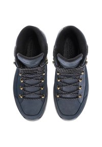 Paar donkerblauwe wandelschoenen met zwart-witte veters, gouden oogjes en gewatteerde zwarte kraag, gezien van bovenaf op een witte achtergrond.