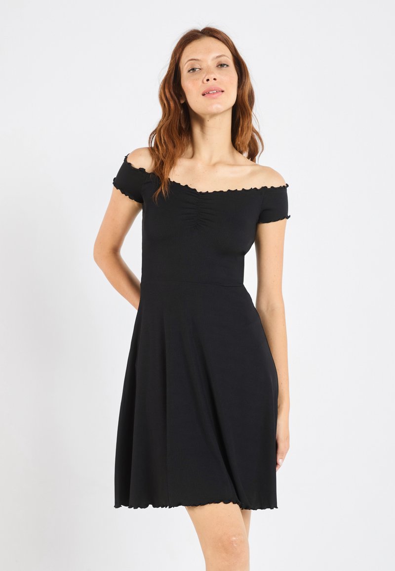 Rochie neagră cu umerii la vedere, cu textură ribbed, corset ajustat, fustă evazată și margini zimțate. Adunări subtile la bust.