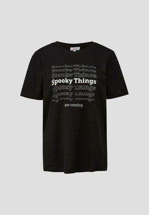 T-shirt en coton noir avec le texte blanc et gris "Des choses effrayantes arrivent" dans des tailles et orientations variées, manches courtes, col rond.
