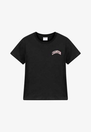 T-shirt noir à manches courtes et col rond avec un petit texte rose "CHAMPION" sur la partie supérieure gauche de la poitrine.