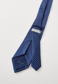 Marineblaue Krawatte mit weißen Punkten, aus strukturiertem Stoff, mit einem Etikett "Michael Kors". Schlanke Form mit spitzen Enden.