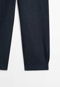 Pantalon en denim foncé à coupe droite, avec une texture lisse, des détails de couture subtils et un design épuré.
