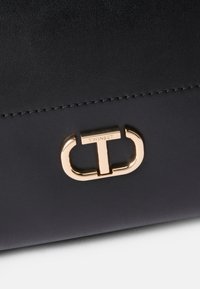 Zwarte nep leren handtas met een goudkleurige sluiting met de merknaam "TWINTSET." Soepele textuur en minimalistisch ontwerp.