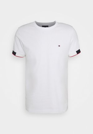 Hvid bomulds t-shirt med korte ærmer, der har røde og marineblå detaljer på ærmekanterne og et lille logo på brystet.