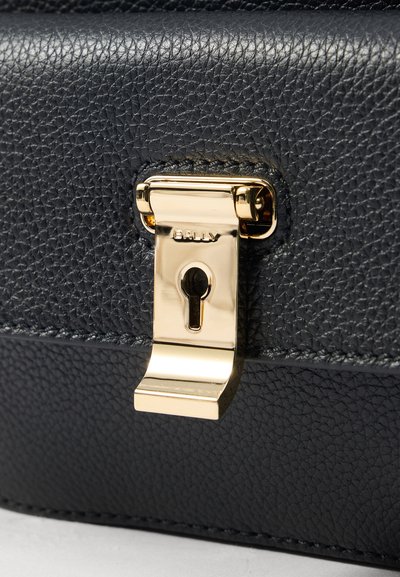 Svart läderväska med texturerad yta, lås med guldfärgad ton och nyckelhål, samt präglad varumärkesdetalj.