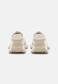 Sport sneakers featuring a white and beige colorway, textured suede accents, padded collar, and a rubber sole with geometric tread design.