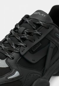 Black and grey Replay sneaker with patterned laces, mesh and synthetic upper, and visible brand logo on tongue and side panel.