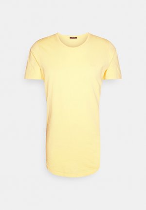 T-shirt jaune doux à manches courtes avec col rond et petit logo sur la poitrine gauche, présenté sur un fond clair uni.