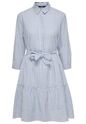 Robe chemise à rayures verticales bleues et blanches, manches longues, col, et ceinture nouée à la taille au-dessus d'une jupe froncée.