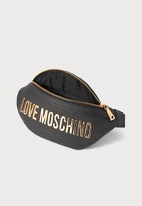 Crna torbica od umjetne kože s zlatnim patentnim zatvaračem i odvažnim natpisom "LOVE MOSCHINO" sprijeda. Glatka tekstura; zakrivljen oblik.