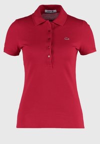 Polo manches courtes rouge pour femme avec boutons et petit logo crocodile brodé sur la poitrine gauche.