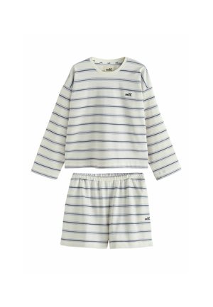 Woman with brown hair in a bun wearing white long-sleeve top and shorts with thin horizontal black stripes and "self." text on back.