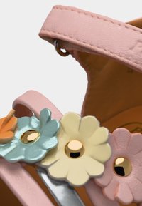 Λουρί ροζ δερμάτινου σανδαλιού με μεταλλικά καρφιά σε σχήμα λουλουδιού σε παστέλ μπλε, κρεμ και ροδακινί, με χρυσά κέντρα.