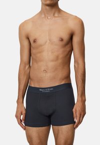 Dunkelblaue Boxershorts aus geripptem Baumwollstoff, mit einem weichen, elastischen Bund, der das Logo "Marc O'Polo" in weißer Schrift zeigt.