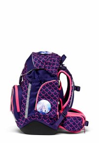 Lila Rucksack mit pinkem Schuppenmuster, reflektierenden Streifen und rundem Schloss-Logo. Verfügt über mehrere Taschen und gepolsterte Riemen für Komfort.