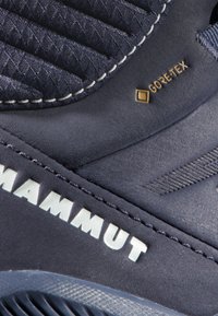 Scarpa Mammut blu con tessuto testurizzato, logo Gore-Tex in evidenza, parte superiore imbottita e dettaglio del marchio bianco; progettata per l'uso all'aperto.