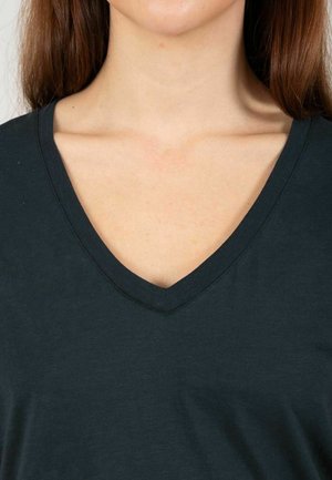 Camiseta negra de cuello en V con una textura suave, que presenta un corte clásico. El escote está rematado con un ribete acanalado.