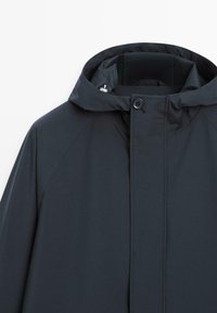 Dunkelblaue wasserdichte Jacke mit Kapuze, vorderer Knopf- und Reißverschluss, und hohem Kragen zum Schutz vor Wetter.