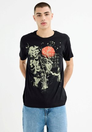 Camiseta de algodón negra con un diseño gráfico que presenta elementos en verde y rojo, representando bambú y patrones abstractos. Corte casual.
